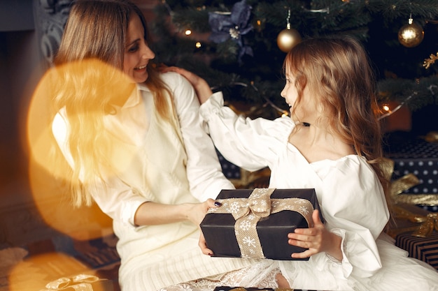 Free photo mother with cute daughter at home near fireplace