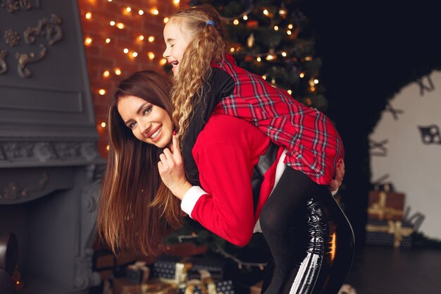 Mother with cute daughter at home near fireplace