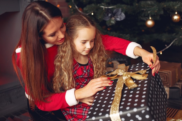 Free Photo mother with cute daughter at home near fireplace