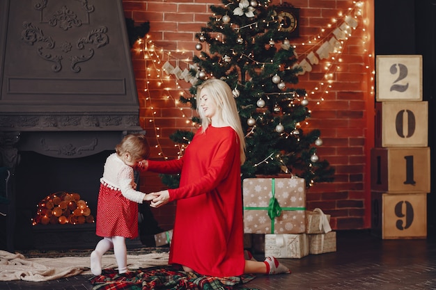 Mother with cute daughter at home in a red dress