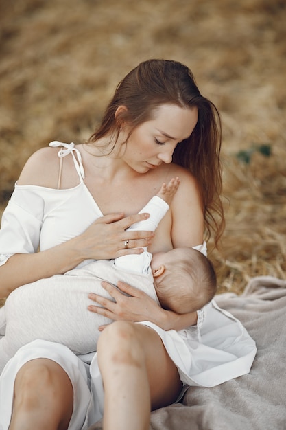 Mother with cute daughter. Mom breastfeeding her little daughter. Woman in a white dress.