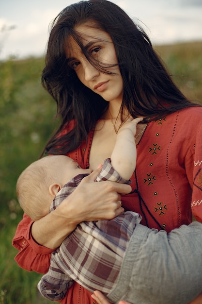 Free photo mother with cute daughter. mom breastfeeding her little son. woman in a red dress.