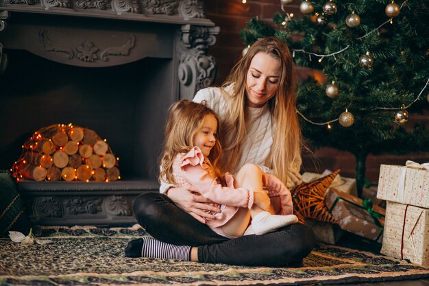 Mother with daughter by christmas tree