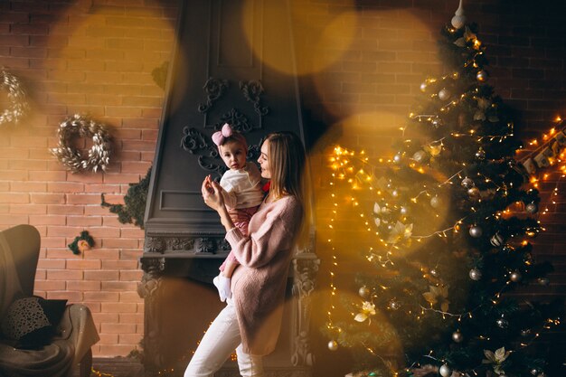 Mother with daughter by Christmas tree