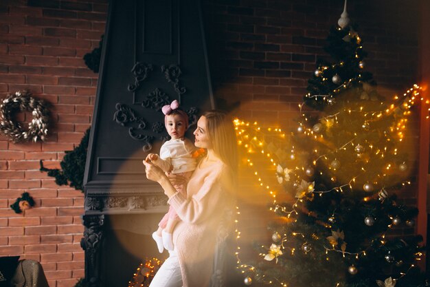 Mother with daughter by Christmas tree