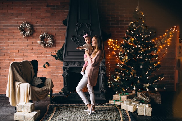 Mother with daughter by Christmas tree