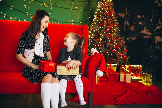 Mother with daughter on Christmas sitting on sofa with presents