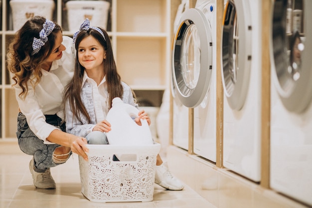 Mother with daughter doing laundry at self serviece laundrette