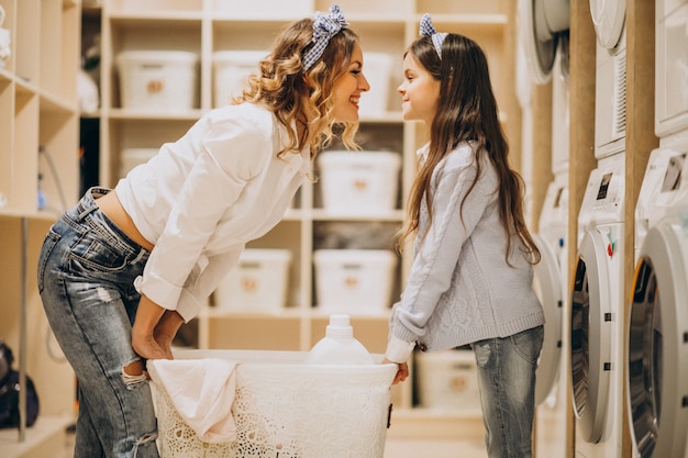 Mother with daughter doing laundry at self serviece laundrette