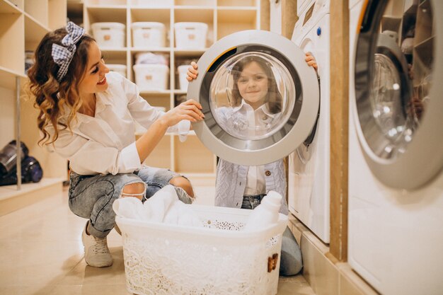 Mother with daughter doing laundry at self serviece laundrette