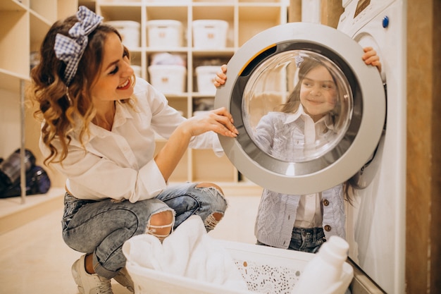 Mother with daughter doing laundry at self serviece laundrette