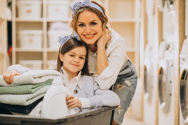 Free photo mother with daughter doing laundry at self serviece laundrette