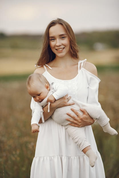 Mother with daughter. Family in a field. Newborn girl. Woman in a white dress.