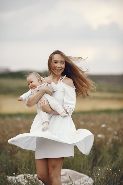 Mother with daughter. Family in a field. Newborn girl. Woman in a white dress.