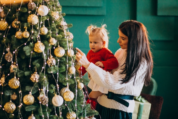 Mother with daughter hanging toys on Christmas tree