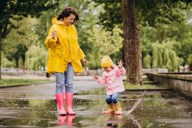 Mother with daughter having fun jumping in puddles