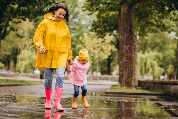 Mother with daughter having fun jumping in puddles