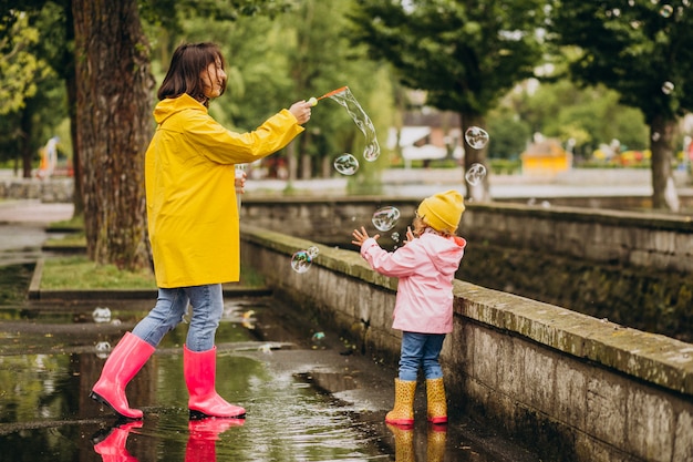 Mother with daughter having fun in park in a rainy weather