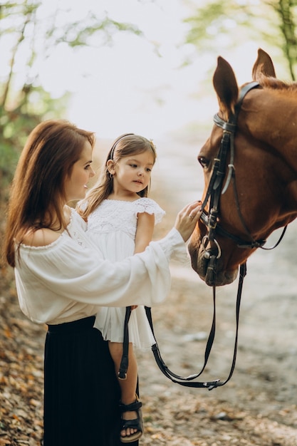 Mother with daughter and horse in forest