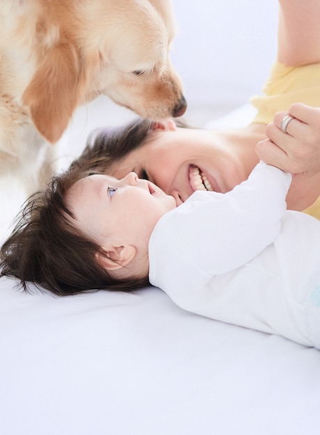 The mother with daughter lie on the bed and dog looking at them