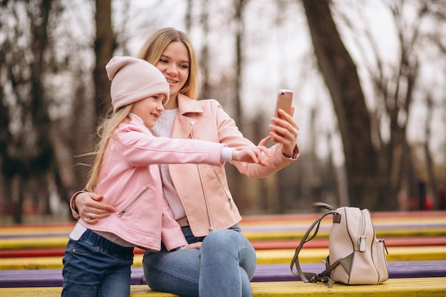 Free photo mother with daughter making selfie outside in park