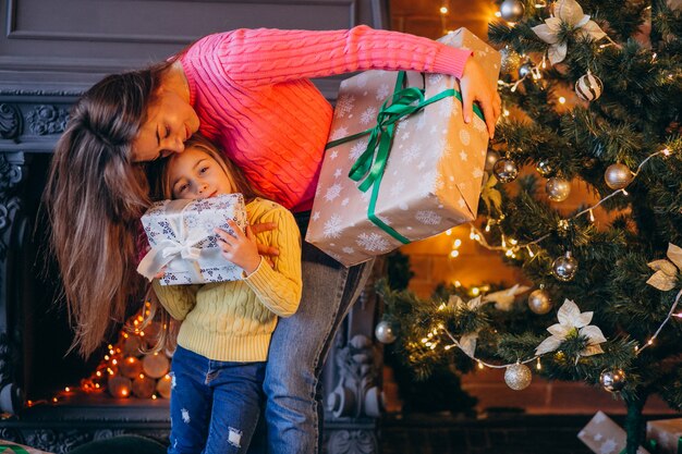 Mother with daughter packing present by fireplace on Christmas