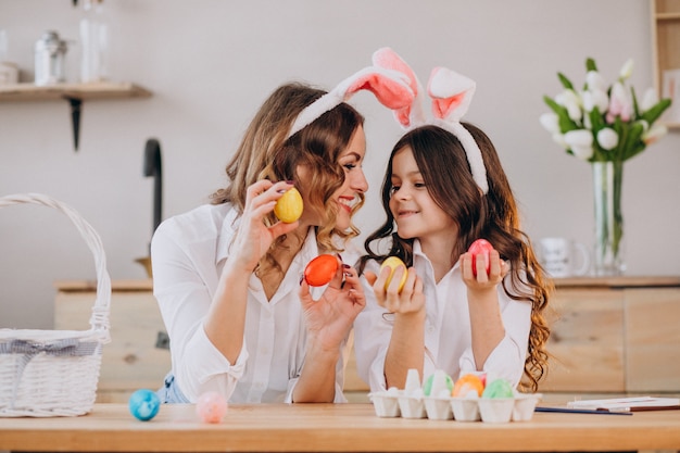 Mother with daughter painting eggs for easter