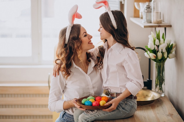 Mother with daughter painting eggs for easter