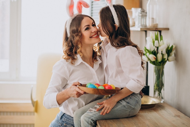 Mother with daughter painting eggs for easter