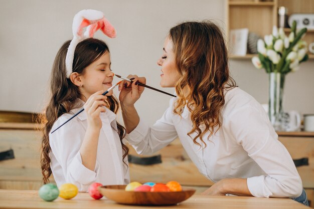 Mother with daughter painting eggs for easter