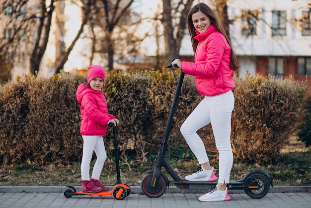 Mother with daughter riding electric scooter