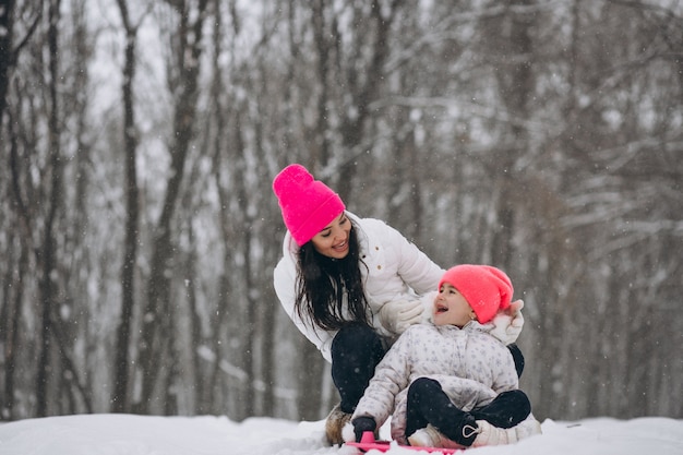 Mother with daughter riding on plate in winter park