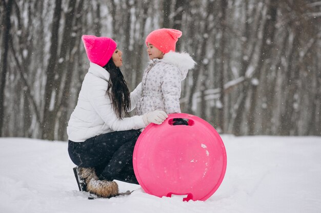 Mother with daughter riding on plate in winter park