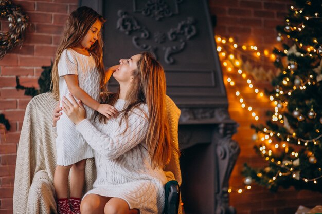 Mother with daughter sitting in chair by Christmas tree