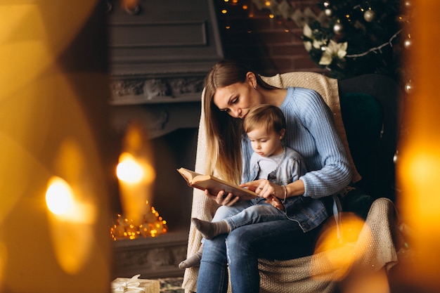 Free Photo mother with daughter sitting in chair by christmas tree