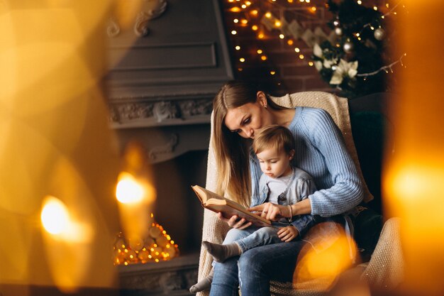 Mother with daughter sitting in chair by Christmas tree