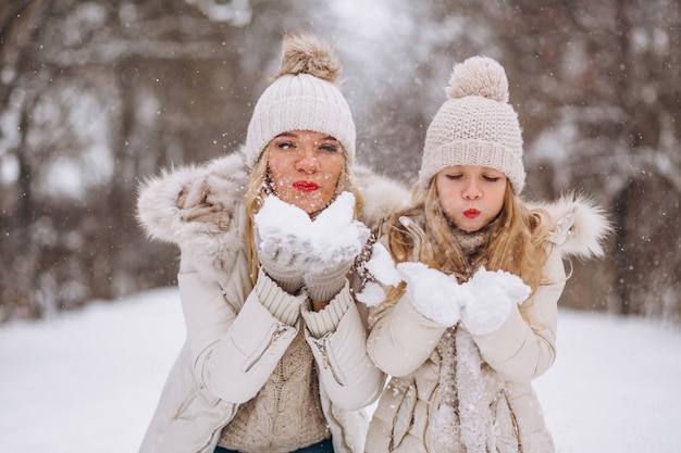 Mother with daughter walking together in a winter park