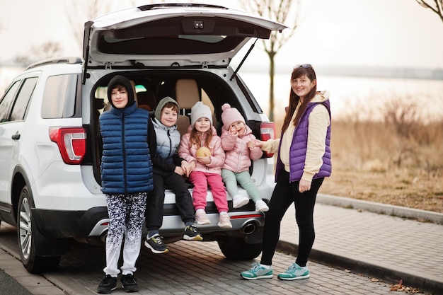 Free photo mother with four kids sitting in trunk of big suv car