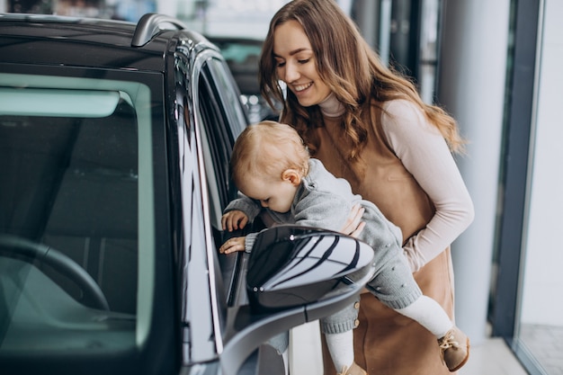 Free photo mother with her baby daughter in a car showroom