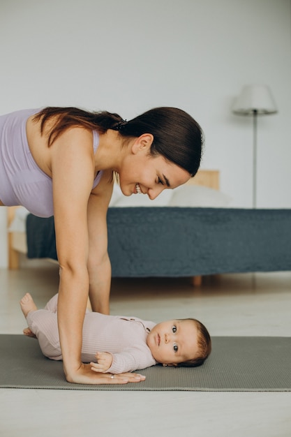 Mother with her baby daughter practice yoga at home