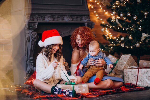 Mother with her daughter and son on Christmas by Christmas tree