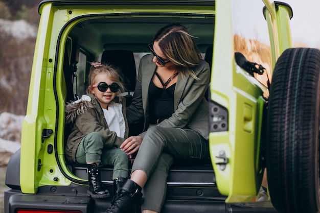 Mother with her little daugher sitting in the back of the car