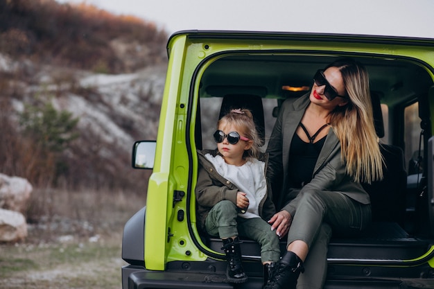 Mother with her little daugher sitting in the back of the car