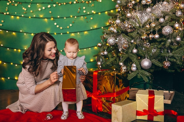 Mother with her little daughter by the Christmas tree