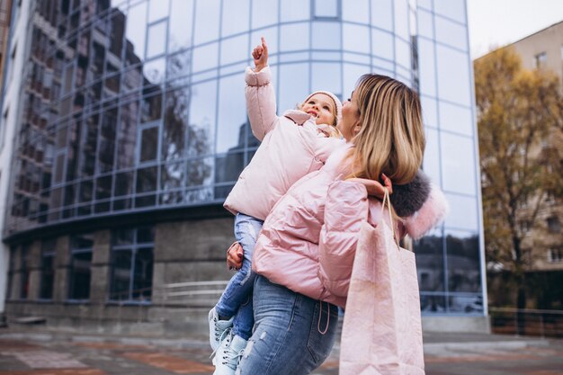 Mother with her little daughter dressed in warm cloth aoutside the street