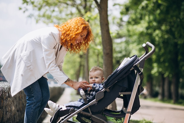 Mother with her little son in a baby carriage in park