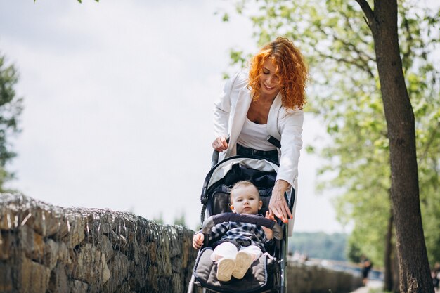 Mother with her little son in a baby carriage in park