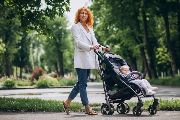 Free photo mother with her little son in a baby carriage in park