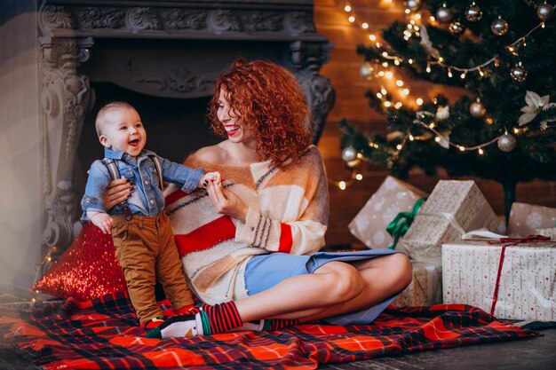 Mother with her little son by the Christmas tree with presents