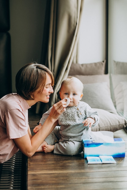 Mother with her little son using napkins for runny nose